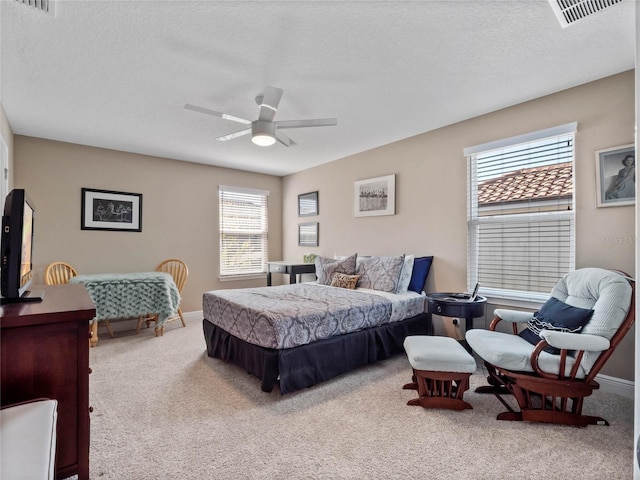 carpeted bedroom with a ceiling fan, baseboards, visible vents, and a textured ceiling