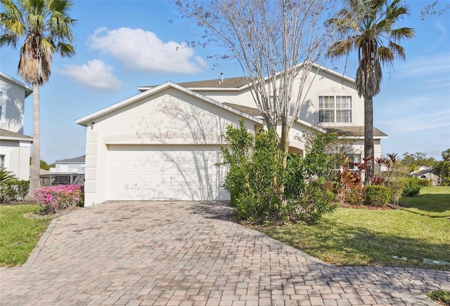 view of front of home with a front yard, decorative driveway, a garage, and stucco siding