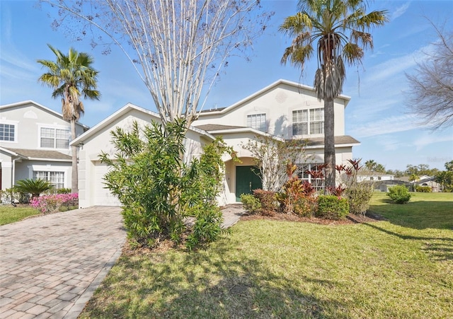 view of front of home with stucco siding, a front yard, decorative driveway, and a garage