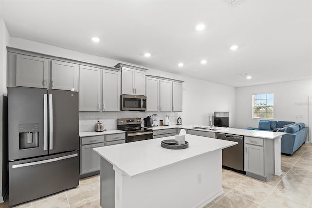 kitchen with open floor plan, light countertops, gray cabinets, a peninsula, and stainless steel appliances