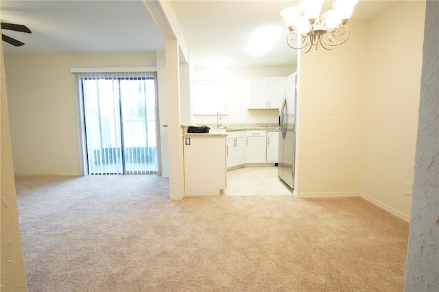 interior space featuring a sink, baseboards, light colored carpet, and ceiling fan with notable chandelier