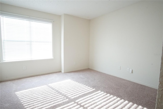 carpeted spare room featuring baseboards