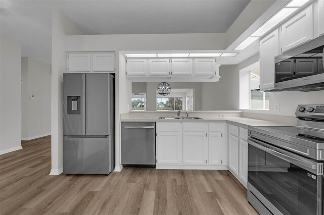 kitchen featuring a sink, appliances with stainless steel finishes, white cabinets, and light countertops