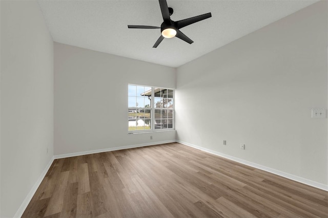 unfurnished room with ceiling fan, a textured ceiling, baseboards, and wood finished floors