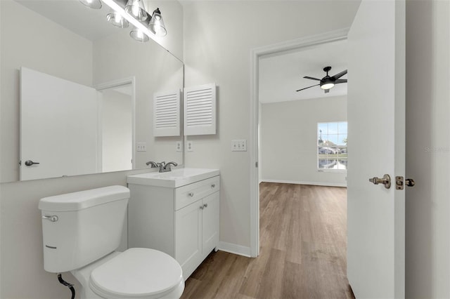 bathroom with vanity, wood finished floors, baseboards, ceiling fan, and toilet