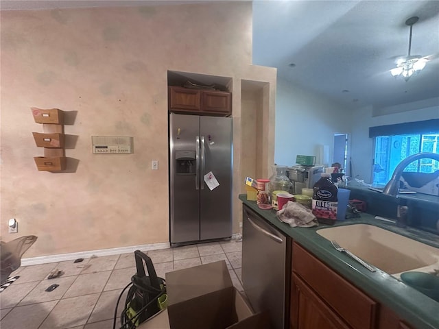 kitchen featuring dark countertops, open floor plan, light tile patterned floors, stainless steel appliances, and a sink