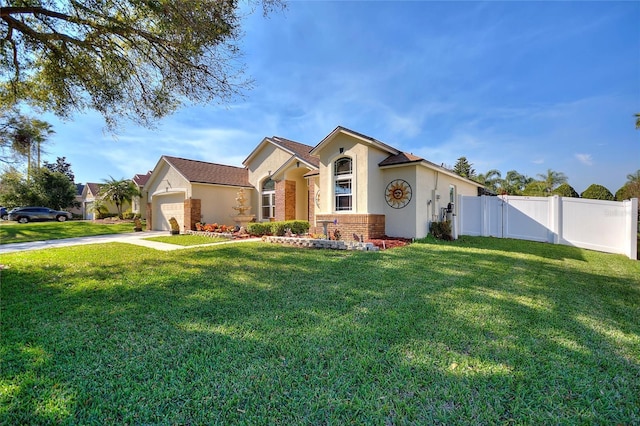 view of front of home featuring stucco siding, fence, a front yard, an attached garage, and brick siding