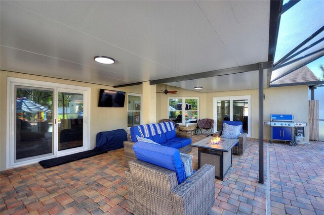 view of patio featuring an outdoor living space with a fire pit, glass enclosure, a ceiling fan, and a grill