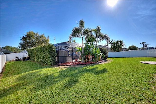 view of yard featuring glass enclosure and a fenced backyard