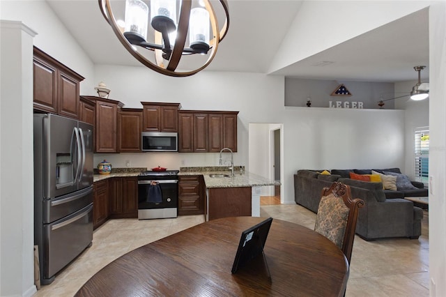 kitchen with open floor plan, light tile patterned floors, stainless steel appliances, high vaulted ceiling, and a sink