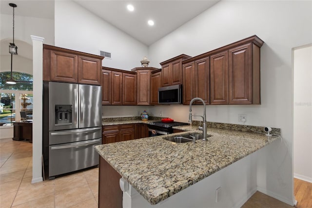 kitchen with visible vents, light stone countertops, a peninsula, stainless steel appliances, and a sink