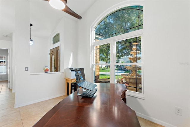 office featuring a high ceiling, light tile patterned floors, baseboards, and a wealth of natural light