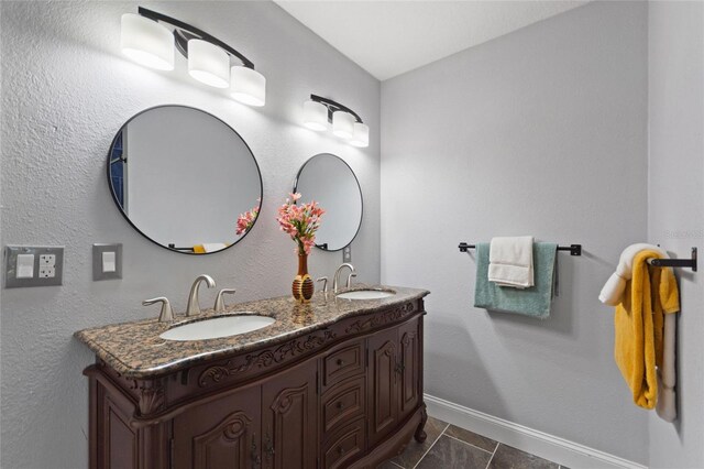 bathroom with a sink, baseboards, and double vanity