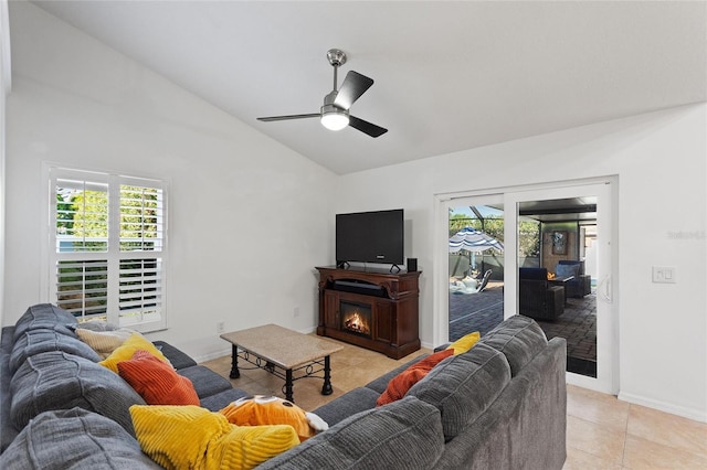 living room with a warm lit fireplace, light tile patterned flooring, baseboards, and a wealth of natural light