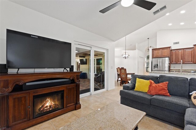 living room featuring vaulted ceiling, visible vents, a ceiling fan, and a glass covered fireplace