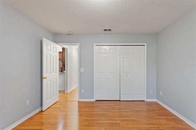 unfurnished bedroom featuring visible vents, baseboards, a closet, and light wood-style flooring