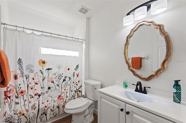 full bath featuring vanity, a shower with shower curtain, toilet, and visible vents