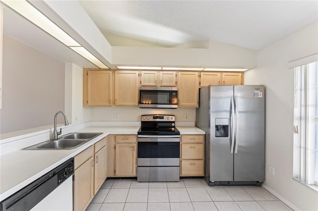 kitchen featuring a sink, lofted ceiling, appliances with stainless steel finishes, and light brown cabinetry