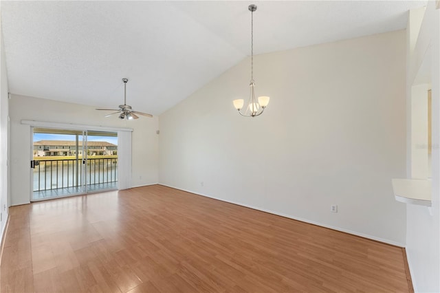 empty room featuring light wood finished floors, ceiling fan with notable chandelier, and high vaulted ceiling