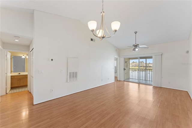 empty room with ceiling fan with notable chandelier, visible vents, light wood finished floors, and high vaulted ceiling