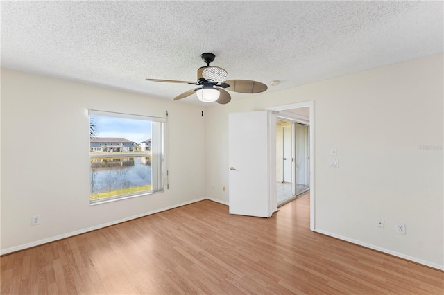 empty room with ceiling fan, wood finished floors, baseboards, and a textured ceiling