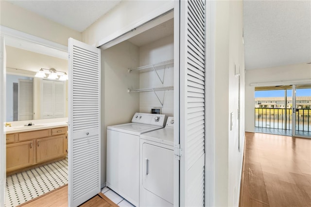 washroom with light wood finished floors, laundry area, independent washer and dryer, and a sink