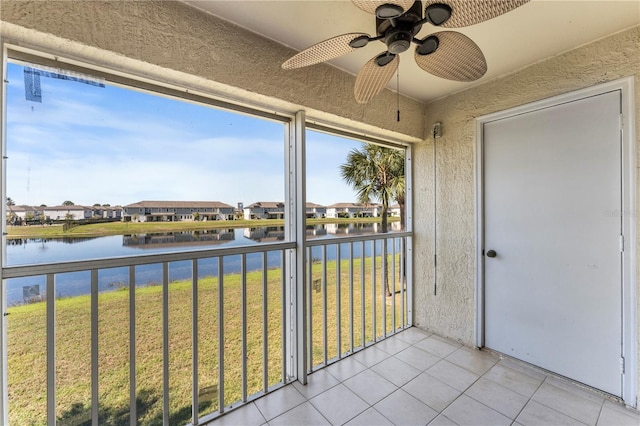 unfurnished sunroom featuring a residential view, a water view, and ceiling fan