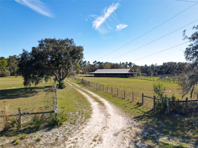 view of street with a rural view and dirt driveway