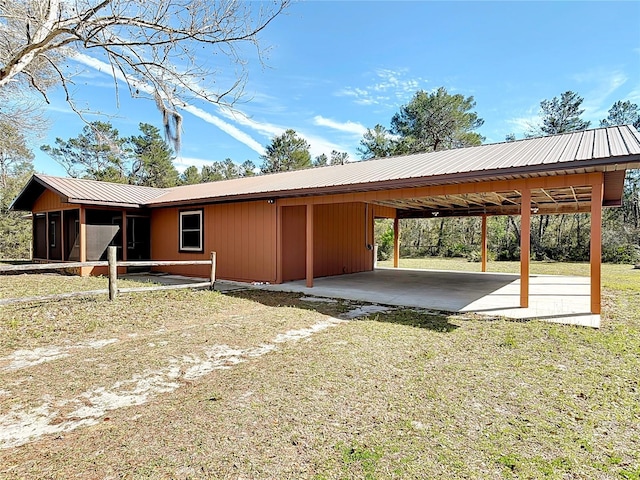 view of home's exterior with a carport, metal roof, an outdoor structure, and dirt driveway