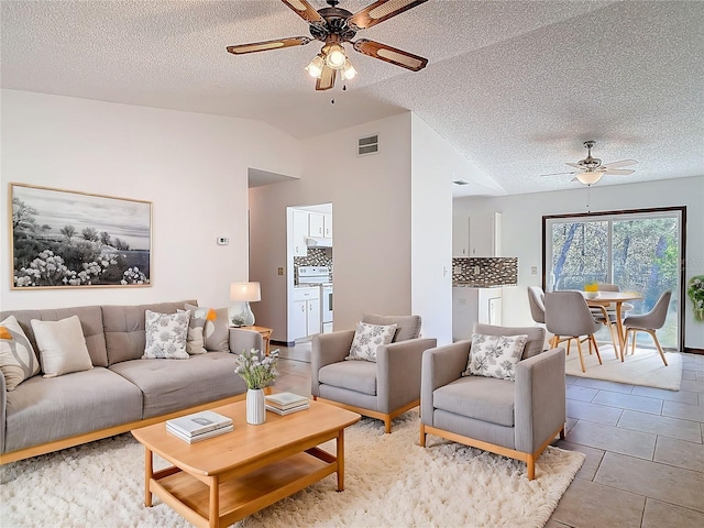 living area with visible vents, a textured ceiling, light tile patterned flooring, ceiling fan, and vaulted ceiling