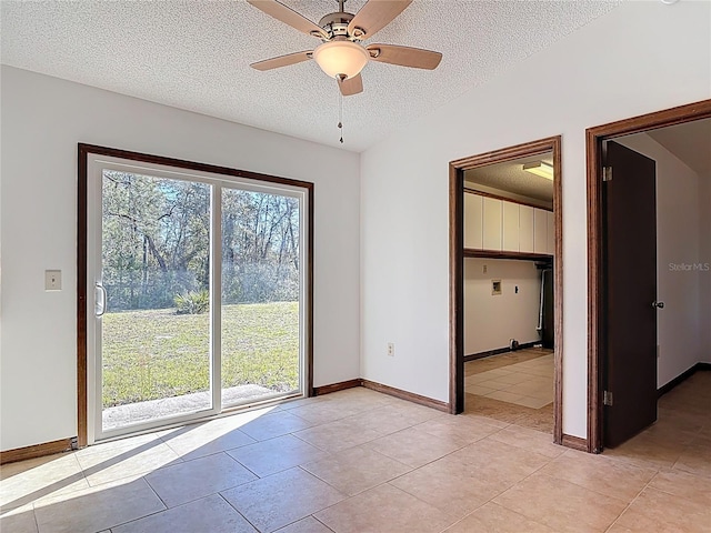 empty room with ceiling fan, light tile patterned flooring, baseboards, and a textured ceiling