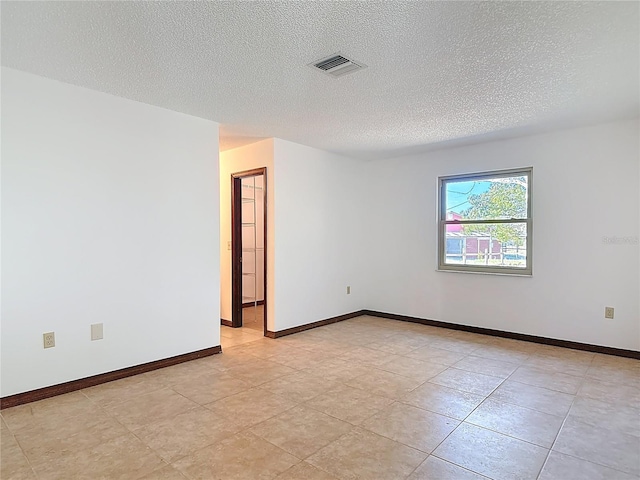 spare room featuring visible vents, baseboards, and a textured ceiling