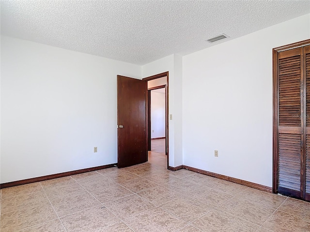 spare room with visible vents, a textured ceiling, and baseboards