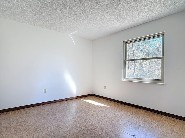 spare room featuring a textured ceiling and baseboards