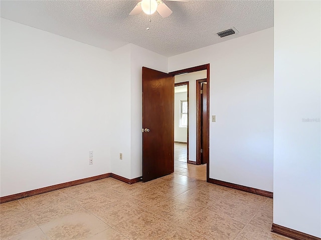 empty room featuring visible vents, baseboards, a textured ceiling, and a ceiling fan