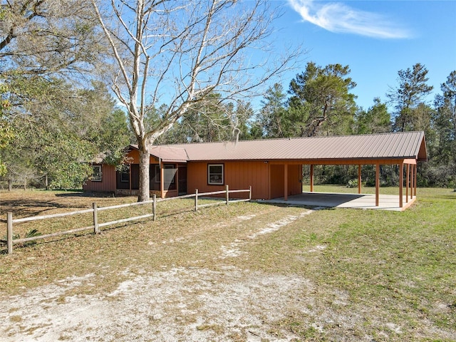 view of front facade with metal roof, an attached carport, and driveway