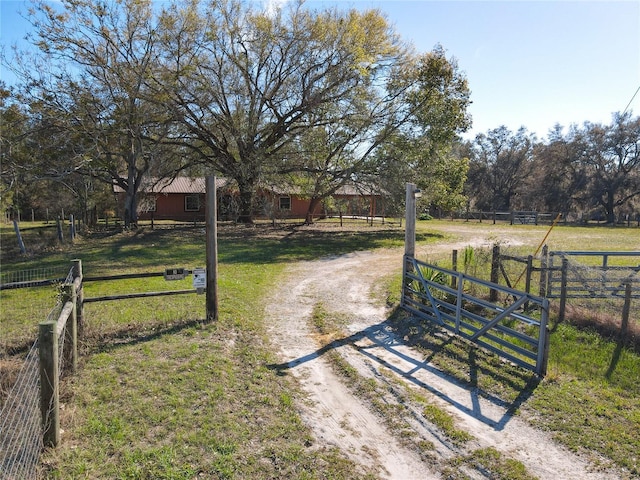 view of yard with a rural view, dirt driveway, and fence