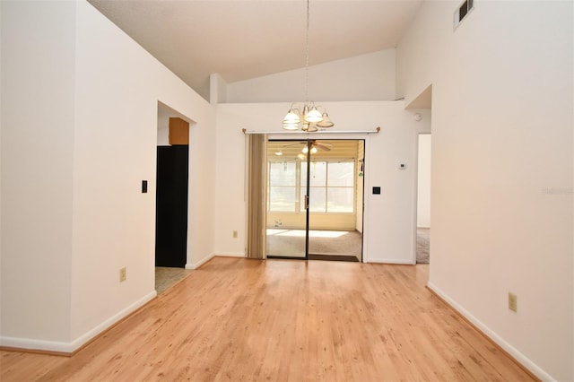 empty room featuring visible vents, baseboards, high vaulted ceiling, and light wood-style flooring