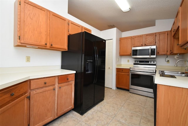 kitchen featuring light tile patterned floors, appliances with stainless steel finishes, light countertops, and a sink