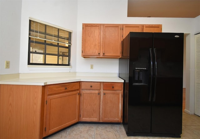 kitchen featuring brown cabinets, black refrigerator with ice dispenser, and light countertops