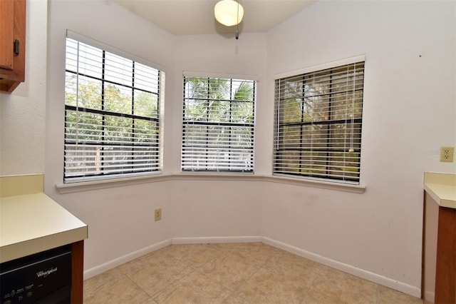 unfurnished dining area with light tile patterned floors and baseboards