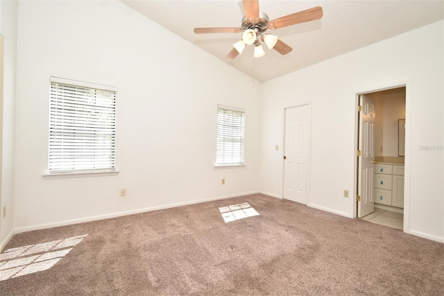 unfurnished bedroom featuring a ceiling fan, connected bathroom, carpet, baseboards, and vaulted ceiling