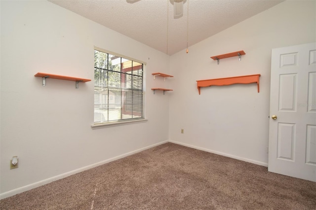 spare room featuring a ceiling fan, carpet, baseboards, vaulted ceiling, and a textured ceiling