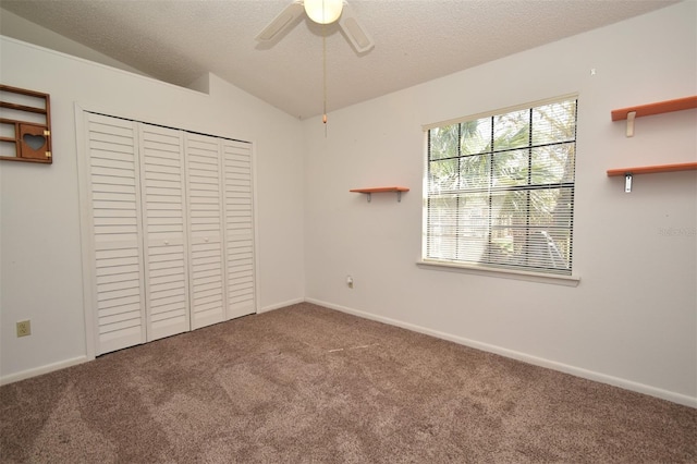 unfurnished bedroom featuring vaulted ceiling, carpet, a closet, and a textured ceiling