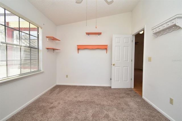 carpeted empty room featuring a textured ceiling, baseboards, and vaulted ceiling