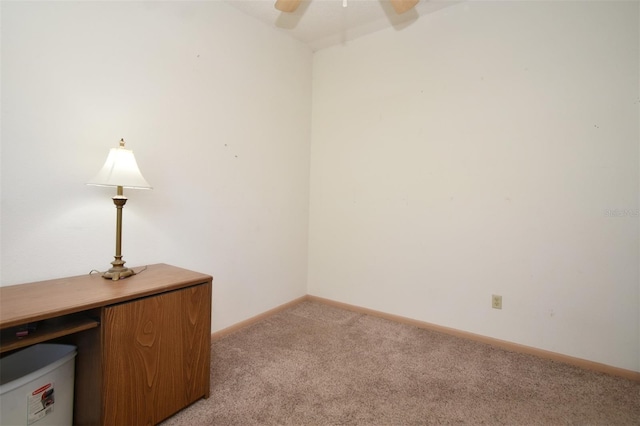 unfurnished office with light colored carpet, a ceiling fan, and baseboards