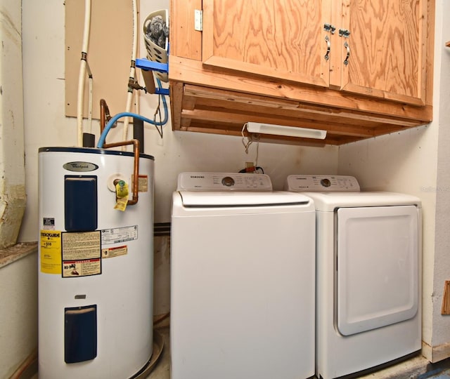 clothes washing area featuring water heater, cabinet space, and washer and clothes dryer