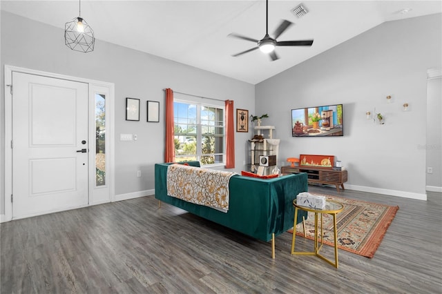 living area featuring visible vents, wood finished floors, baseboards, ceiling fan, and vaulted ceiling