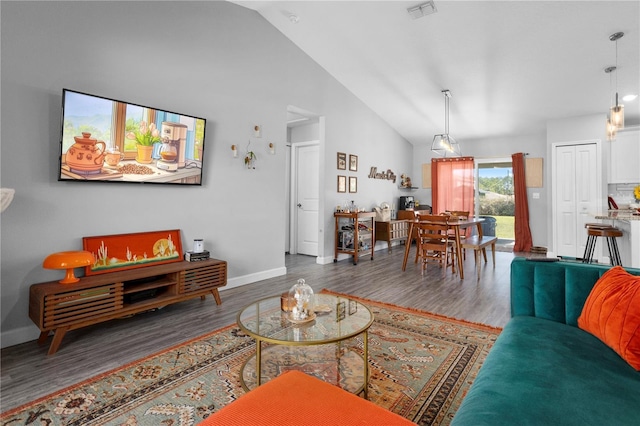 living area featuring high vaulted ceiling, wood finished floors, visible vents, and baseboards