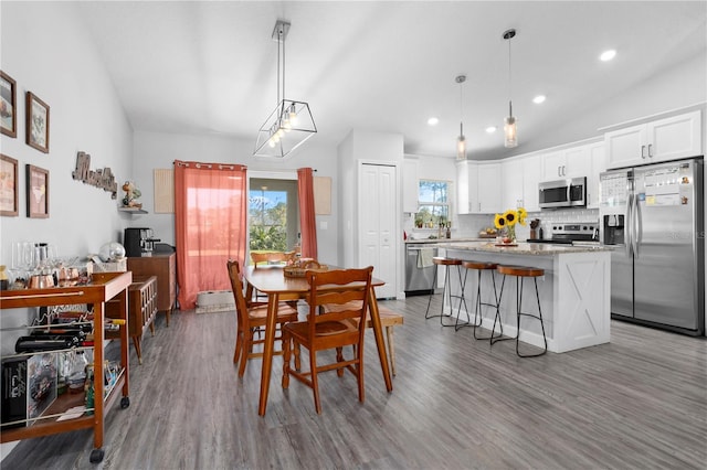 dining space with recessed lighting, lofted ceiling, and wood finished floors